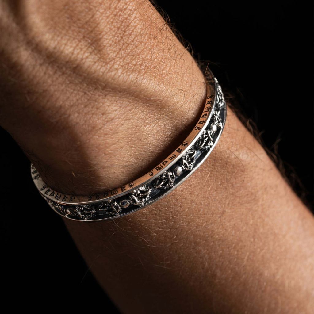 Close-up of a man’s wrist wearing the Ronatelli Basel 10 mm Tibetan 925 sterling silver cuff bracelet, engraved script along the edge and an oxidized center band