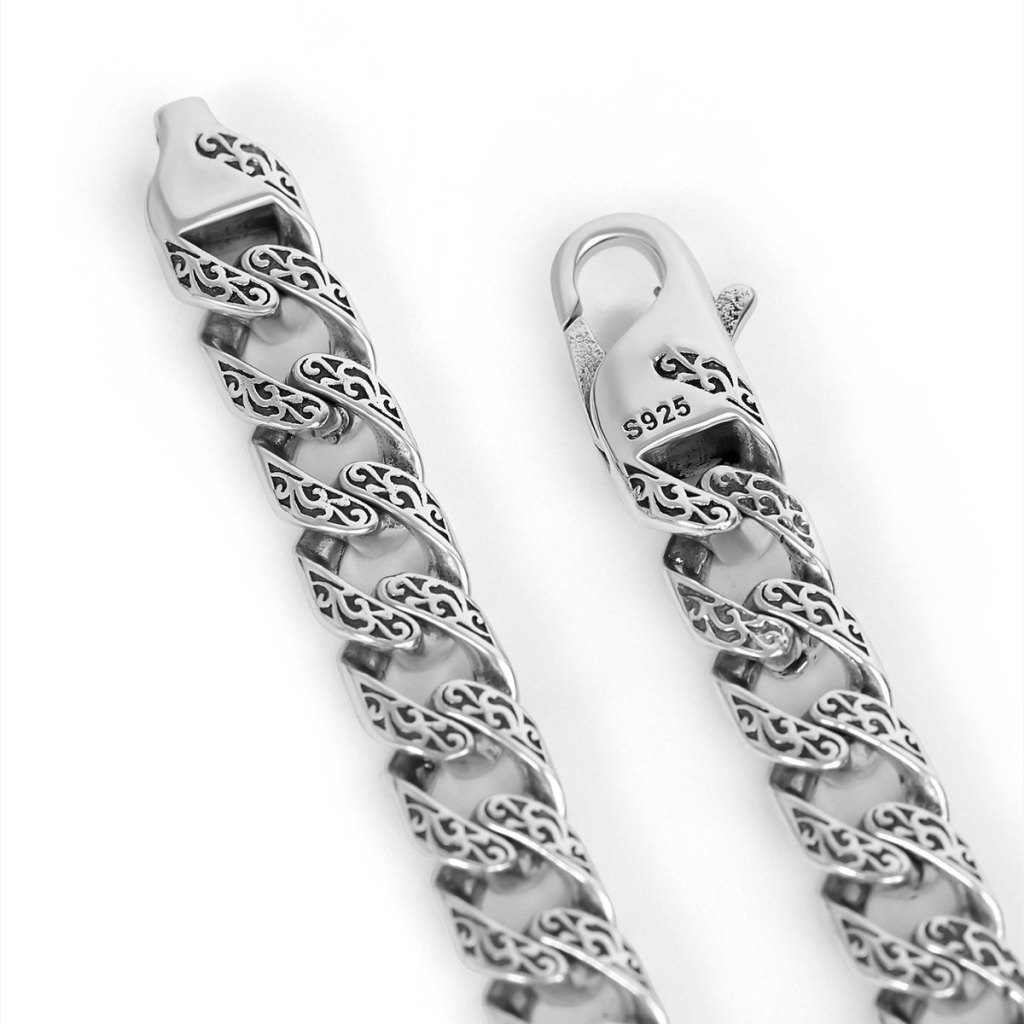Close-up of the Ronatelli Fulda 7 mm engraved curb chain in 925 sterling silver: scrollwork darkened in the recesses of every link, and a lobster clasp stamped S925
