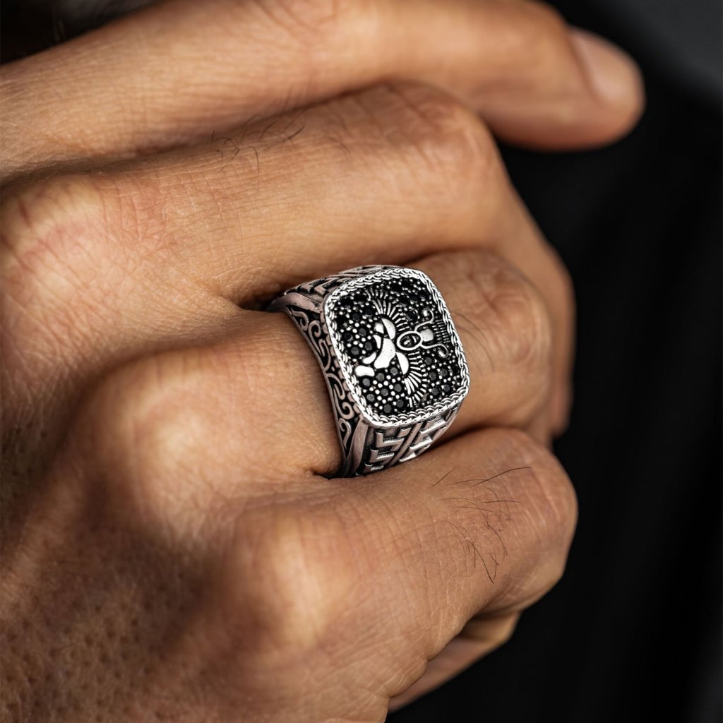 Close-up of a hand wearing the Ronatelli Horus 925 sterling silver signet ring, a winged Faravahar motif on small black onyx stones