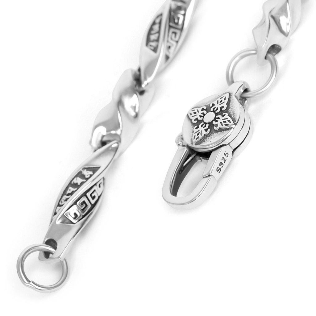 Close-up of the Ronatelli Krun 5 mm scroll link chain in 925 sterling silver: twisted links with darkened Greek-key and script-style panels, and a lobster clasp with a double vajra disc, stamped S925