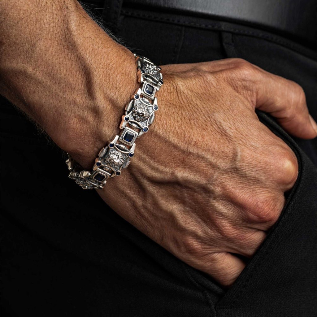 Man with his hand in his pocket, wearing the Ronatelli Leo 18 mm 925 sterling silver bracelet with sculpted lion heads and blue stones