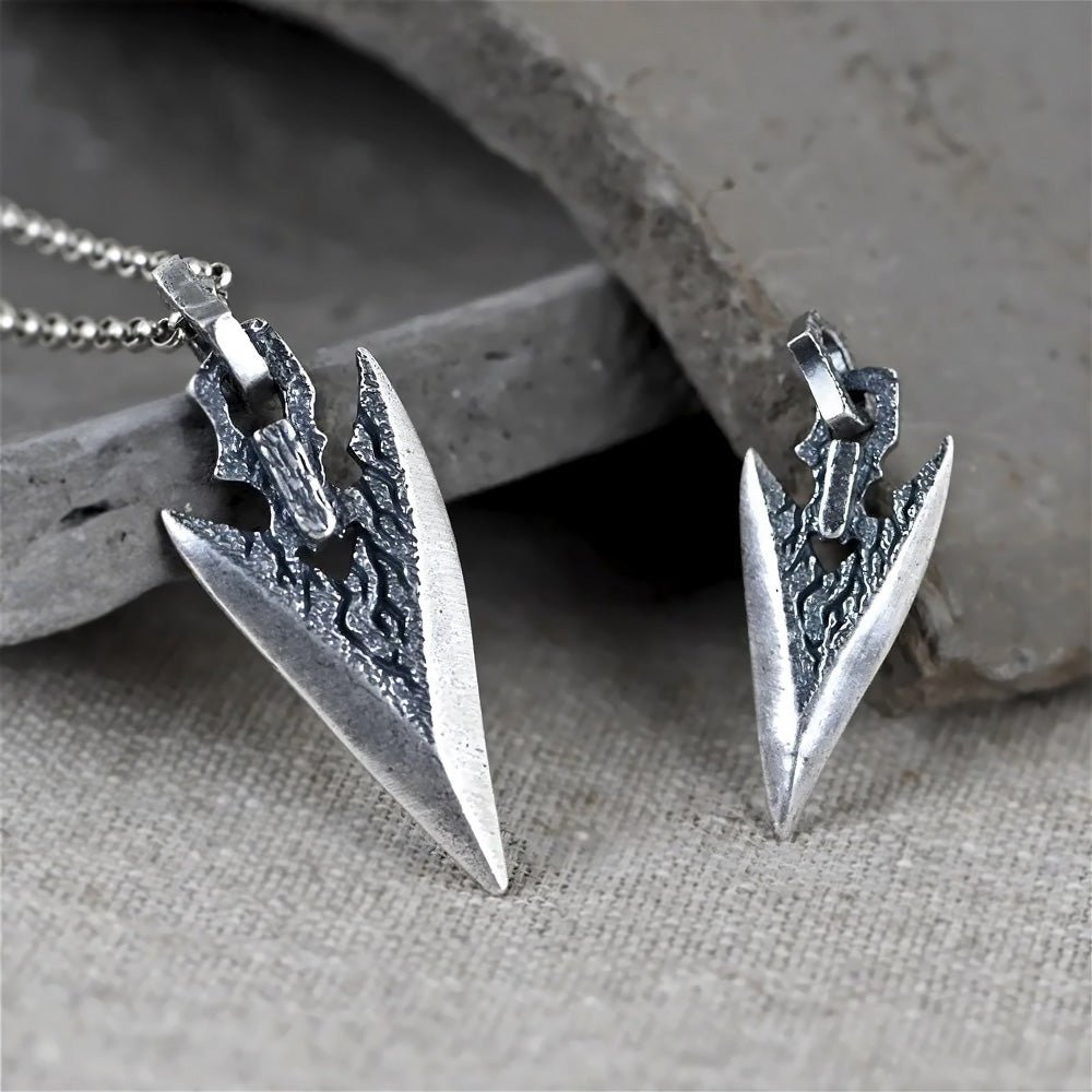 Two Ronatelli Lyon arrowhead 925 sterling silver pendants side by side on a stone, the large size on the left and the small size on the right, both with a weathered, darkened texture