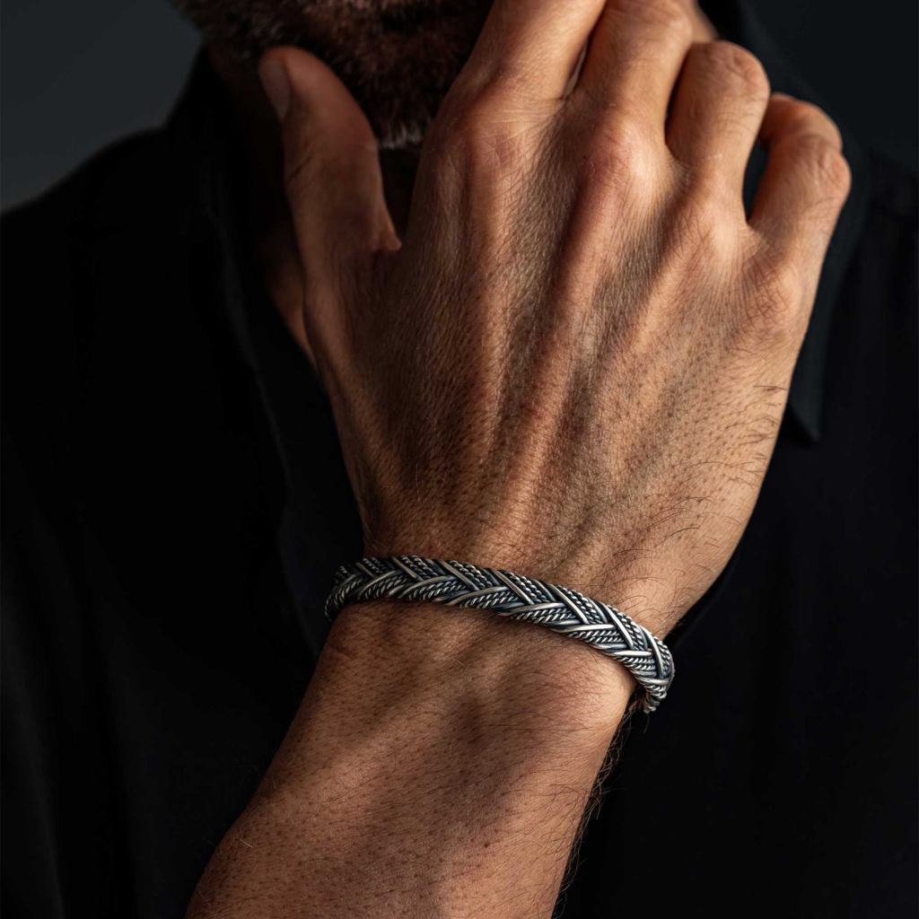 Man with his hand at his chin, wearing the Ronatelli Milan 10 mm twisted 925 sterling silver cuff bracelet