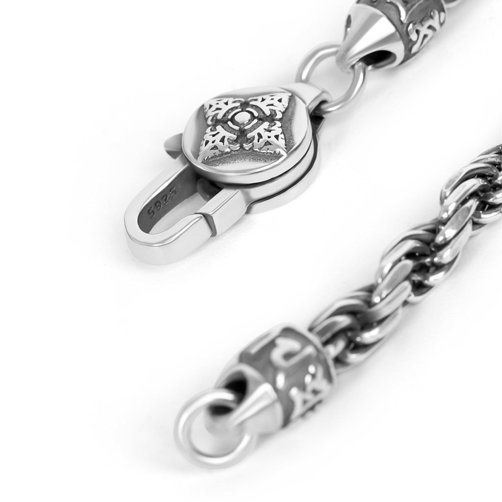 Close-up of the Ronatelli Monza rope chain’s ends: an engraved cone-shaped end cap, a closed ring, and a lobster clasp stamped S925, with the darkened twist of the rope beside it