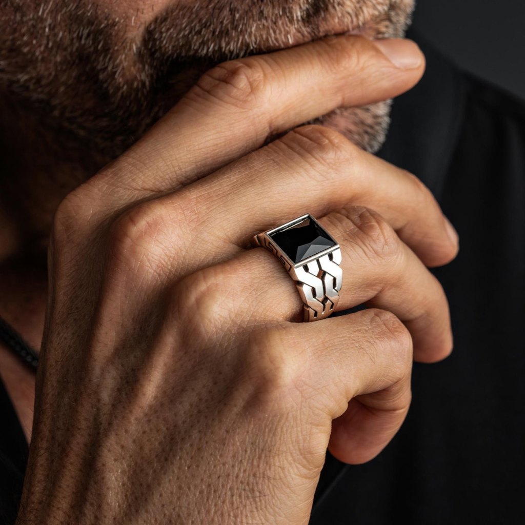 Man with his hand at his chin wearing the Ronatelli Ragnar 925 sterling silver ring with a square black onyx