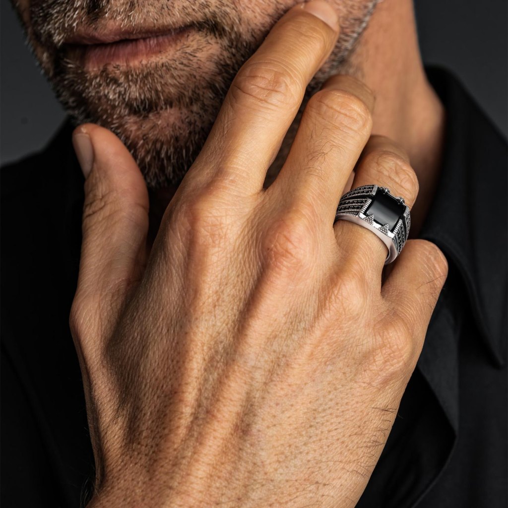Man with his hand at his chin wearing the Ronatelli Troy 925 sterling silver ring with a black onyx and rows of small black stones